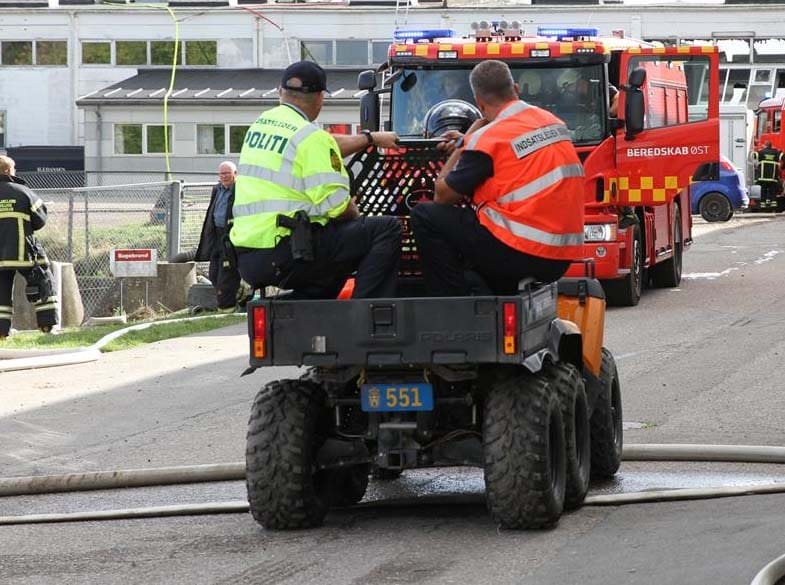 Indsatsleder Politi og Indsatsleder Brand koordinerer en hændelse på ladet af en ATV med en brandbil i baggrunden.
